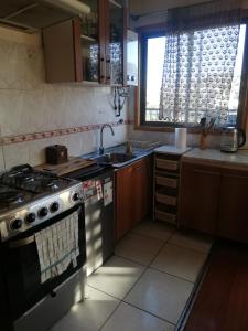 a kitchen with a stove and a sink and a window at Departamento 4 personas central in Viña del Mar