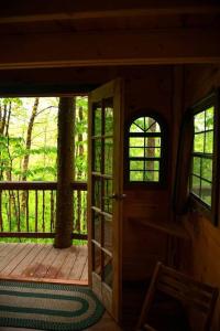 Maine Woods Treehouse-The Birdie في North Lovell: باب مفتوح لكابينة مع شرفة