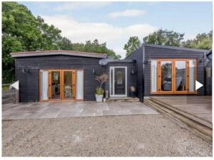 a black house with glass doors and windows at Lillibelles lodge,Oak tree farm in Ashford
