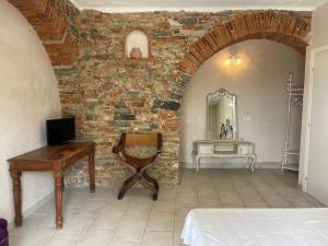 Habitación con pared de piedra, mesa y espejo. en Amore a prima vista b&b en Campiglia Marittima