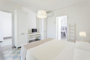 a white bedroom with a bed and a tv at Podere40 Country Hotel in Porto Cesareo