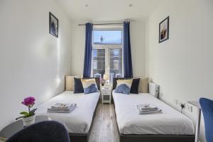 two beds in a small room with a window at The Finsbury Deluxe Apartments in London