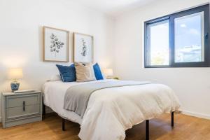 um quarto branco com uma cama grande e almofadas azuis em LUX House em Ponta Delgada