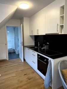 uma cozinha com armários brancos e um balcão preto em penthouse-studio centrally located in Zurich em Zürich