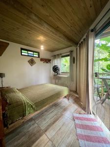 a bedroom with a bed and a large window at Hospedagem Casa Maracujá in Trindade