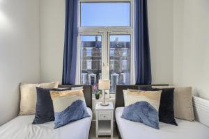 two beds in a room with a window at The Finsbury Deluxe Apartments in London