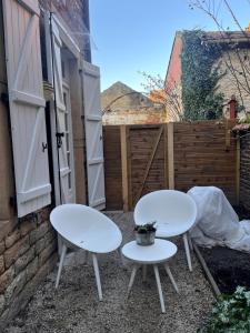 2 weiße Tische und Stühle auf einer Terrasse in der Unterkunft L'ARCADE in Louhans