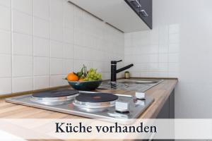 a kitchen counter with a bowl of fruit and a sink at Relax Apartment 1302 Tolle Aussicht Massagesessel Smart TV in Augsburg