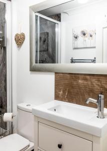 een witte badkamer met een wastafel en een spiegel bij The Apartment at No.12 in Lochwinnoch