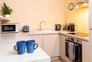 dos tazas azules sentadas en un mostrador en una cocina en The Apartment at No.12, en Lochwinnoch
