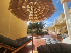 eine Terrasse mit einer Bank und einem Sonnenschirm in der Unterkunft Casita Azul Las Arenas in Caleta de Fuste