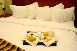 a bed with a tray of food on it at Hotel La Falaise Yaounde in Yaound&eacute;
