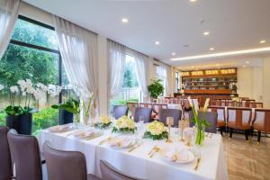 uma sala de jantar com uma mesa longa com toalhas de mesa brancas em Sandals Star Hotel em Ðưc Trọng