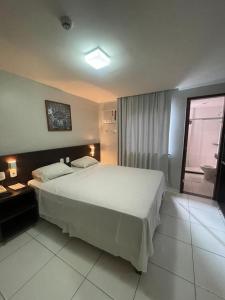 um quarto com uma grande cama branca e uma janela em Absolutte Hotel em Salvador