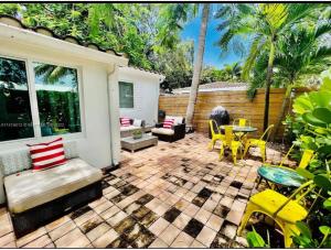 a patio with yellow chairs and a table and chairs at Private Fort Lauderdale cottage in Fort Lauderdale