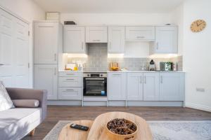 een keuken met witte kasten en een tafel in een kamer bij Free Parking | 2BR | WiFi in Cardiff