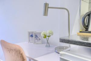 a white table with a vase of flowers and a lamp at The Finsbury Deluxe Apartments in London +29 photos