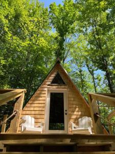 eine Blockhütte mit weißen Stühlen und einer Tür in der Unterkunft Cabin in Maine Woods-The Bogey in North Lovell