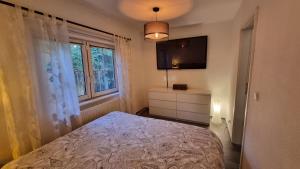 Schlafzimmer mit einem Bett, einem TV und einem Fenster in der Unterkunft Haus am See in Zesch am See in Zossen