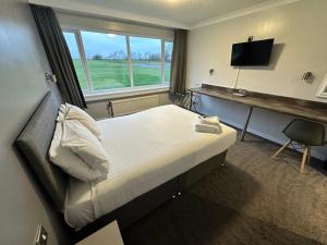 a bedroom with a bed and a desk and a television at Sporting Lodge Inn Middlesbrough in Middlesbrough