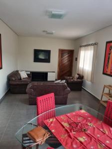 a living room with a glass table and red chairs at O Zóio da cobra é verde in Bragança Paulista