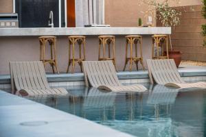 3 sillas sentadas junto a una piscina en Pueblo Viejo Desert Minimalist Pool Home, en Bermuda Dunes