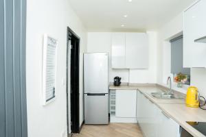 cocina blanca con nevera y fregadero en A modern home close to city centre with parking en Killingbeck