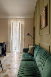 a green couch in a living room with a window at Ziolì in Noto