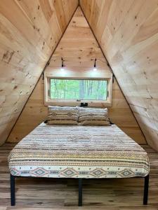ein Bett in einem Holzzimmer mit Fenster in der Unterkunft Rustic Cabin in Maine Woods-The Beech in North Lovell