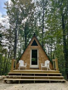 ein kleines Haus mit zwei Stühlen im Wald in der Unterkunft Rustic Cabin in Maine Woods-The Beech in North Lovell