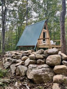 eine Hütte mit einem grünen Dach über einem Haufen Steine in der Unterkunft Rustic Cabin in Maine Woods-The Beech in North Lovell