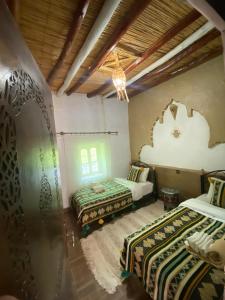 a bedroom with two beds and a chandelier at Casa Mona in Merzouga