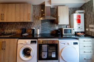 a kitchen with a washing machine and a microwave at Cardiff Getaway - City Center - Free Parking in Cardiff