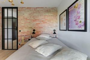 a bedroom with a brick wall and a bed with pillows at Rezydencja Wintera 3 by Grand Apartements in Gdańsk