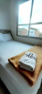 Una cama con una toalla y una ventana en Suite Gold Hotel Omaga en El Peñol
