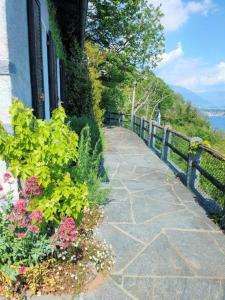 einen steinernen Gehweg neben einem Zaun mit Blumen in der Unterkunft "Pipistrello" 3 Zimmer grosses bezauberndes freistehendes Tessiner Ferienhaus mit unglaublich viel Charme in Ronco sopra Ascona
