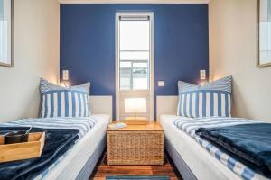 two beds in a room with blue walls at Hausboot Große Freiheit in Ribnitz-Damgarten