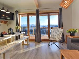 a living room with a large window and a chair at Domki Trzy Tatry in Ząb