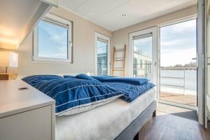 a bedroom with a bed with blue sheets and windows at Hausboot Mein Lieblingsboot in Ribnitz-Damgarten