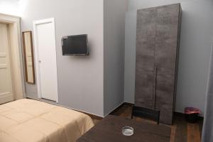 Habitación con cama y TV en la pared. en B&B Palazzo Fischetti en Catania