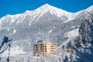 un bâtiment sur le côté d'une montagne enneigée dans l'établissement Panorama Spa Lodges DAS.SCHILLER, à Bad Gastein