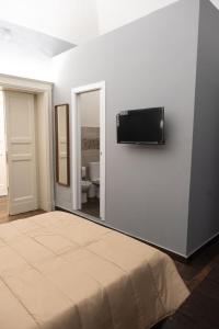 B&B Palazzo Fischetti في كاتانيا: غرفة نوم مع سرير وتلفزيون بشاشة مسطحة على جدار