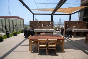 un patio con una mesa de madera y sillas en el techo en New luxury and comfort apartment, fully furnished in Monterrey Centro. (Includes: Pool, Parking lot, A.C., WiFi, Gym), en Monterrey