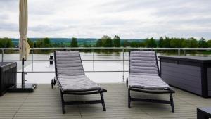 2 sillas sentadas en una terraza con vistas a un cuerpo de agua en Hausboot Möwenschiss - LP3, en Höxter