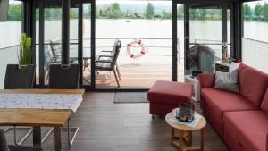 a living room with red furniture and a view of the water at Hausboot Möwenschiss - LP3 in Höxter