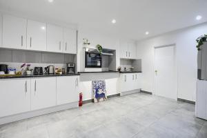 a kitchen with white cabinets and a tile floor at Hackney Central Deluxe Apartment in London