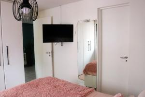 1 dormitorio con TV en la pared y espejo en Apartamento com Varanda vista mar, Max 4 Pessoas, en Fortaleza