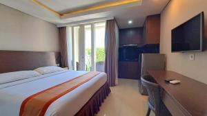 Habitación de hotel con cama, escritorio y TV. en Amed Dream Resort en Amed