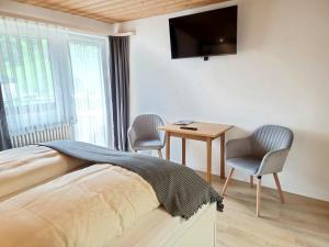 Schlafzimmer mit einem Bett, einem Schreibtisch und einem TV in der Unterkunft Haus Luise in Bad Hindelang