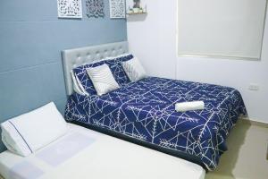 a bedroom with a bed with a blue and white comforter at Apartamento Arenita de mar in Coveñas